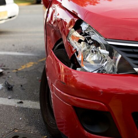 Ein fingierter Verkehrsunfall mit einem roten Auto, dessen rechte Seite und Scheinwerfer kaputt sind