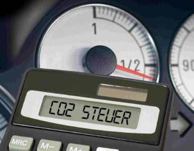 Taschenrechner mit den Worten CO2 Steuer vor dem Armaturenbrett eines Pkws