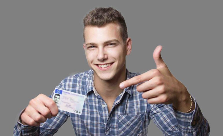 Lächelnder junger Mann hält seinen Führerschein hoch und zeigt darauf.