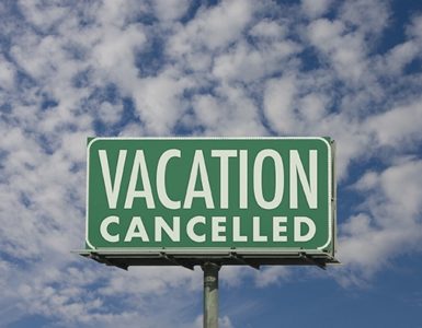Grünes Schild auf dem "Vacation cancelled" steht. Gemeint ist Reiserücktritt aufgrund von Corona.