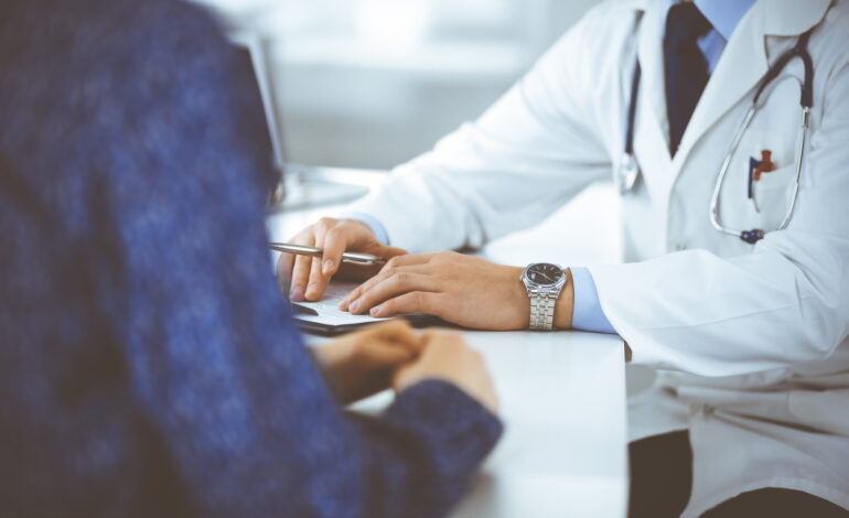 Hände und Schultern zweier Menschen. Patientin sitzt mit Ärztin am Tisch und bespricht ihre Wiedereingliederung.