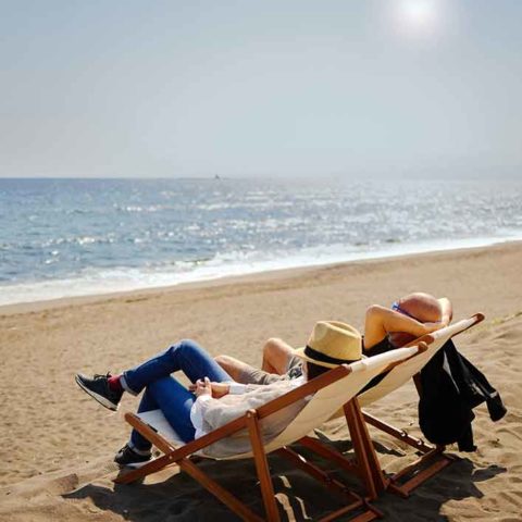 Zwei Personen sitzen am Strand in ihren Strandstühlen