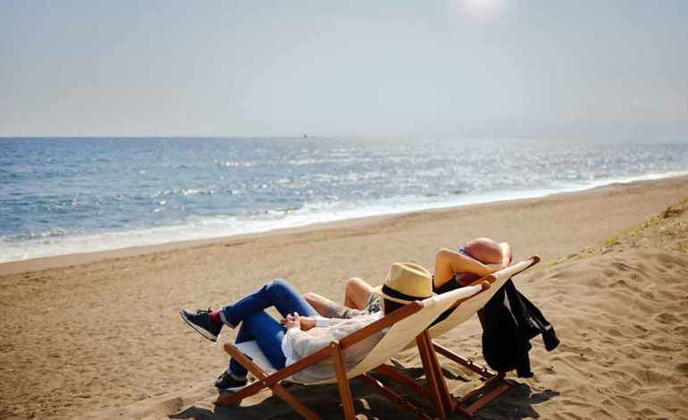 Zwei Personen sitzen am Strand in ihren Strandstühlen