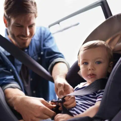 Kleinkind wird im Autositz angegurtet
