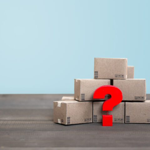 Ein rotes Fragezeichen vor einem Stapel Pakete symbolisiert die Frage: Was tun, wenn da Paket nicht angekommen ist?