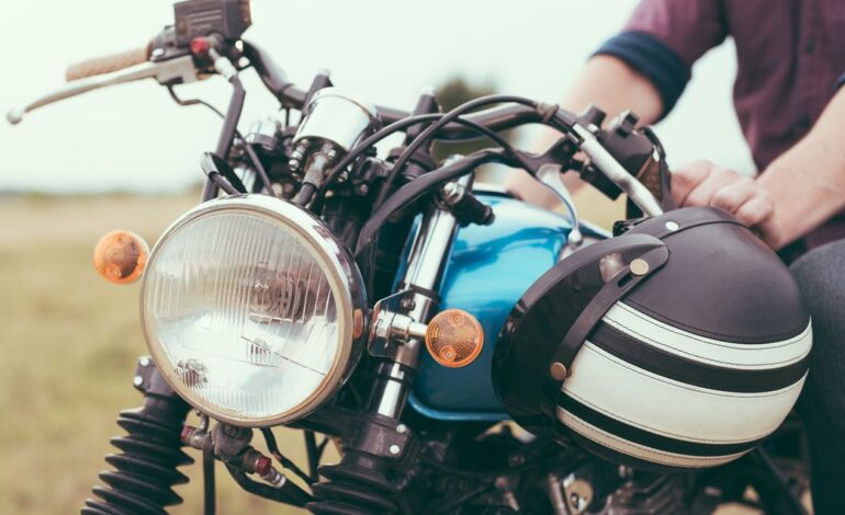 Frontansicht der Motorradbeleuchtung eines geparkten Motorrads, die Hände des Fahrers und der Helm sind auch zu sehen.