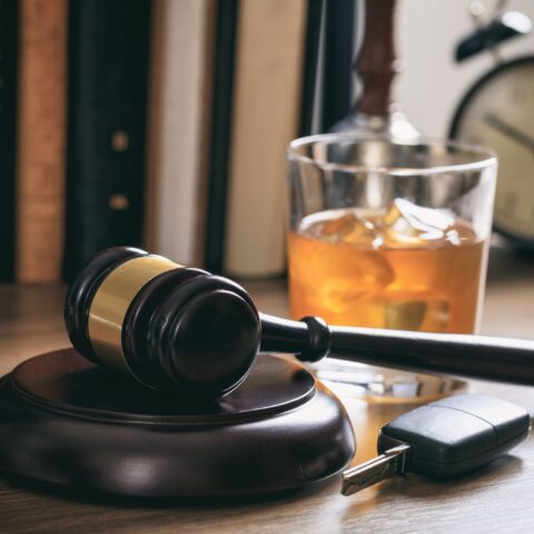 Alkoholglas mit Autoschlüssel und Richterhammer symbolisieren die Strafe für Alkohol am Steuer.