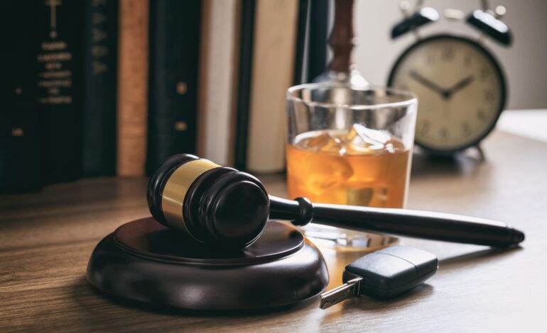 Alkoholglas mit Autoschlüssel und Richterhammer symbolisieren die Strafe für Alkohol am Steuer.