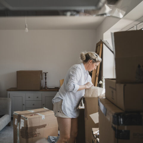 Eine Frau steht in einem Zimmer voller Umzugskisten nach einer Räumungsklage