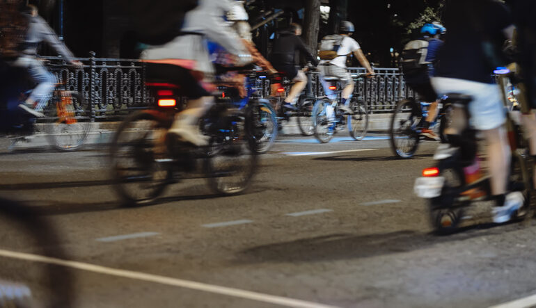 Mehrere Fahrräder mit Fahrradreflektoren auf einer dunklen Straße.