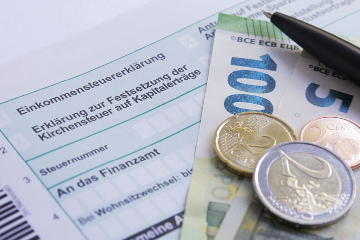 Ein Ausdruck der Einkommensteuererklärung, darauf liegen Münzen und Geldscheine.