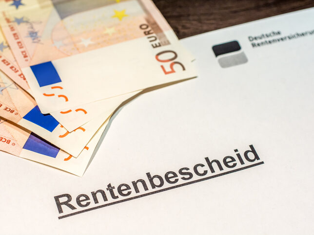 Ausgedruckter Rentenbescheid Dezember 2025, darauf liegen 50-Euro Scheine.