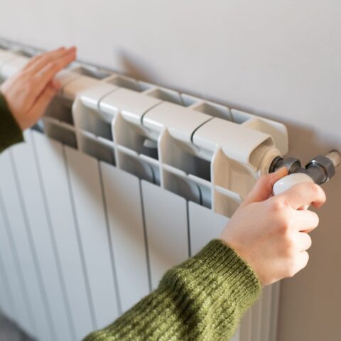 Person prüft Heizkörper bei Heizungsausfall