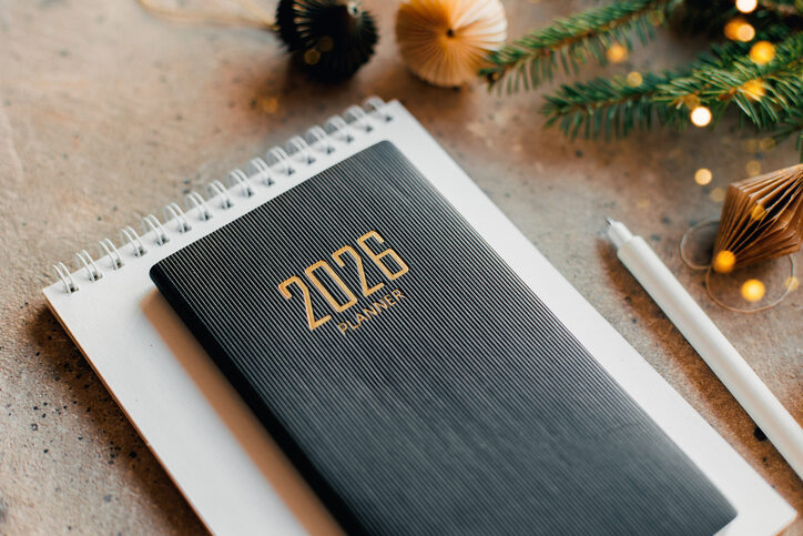 Ein Tisch, auf dem ein Block, ein Stift und ein Jahresplaner für die Neuerungen 2026 liegen. Daneben noch Tannenzweige und andere Weihnachtsdekoration.
