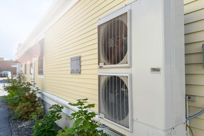 Doppelte Wärmepumpe an einer gelben Hauswand, die als Neuerung ab Januar 2026 leiser sein muss.