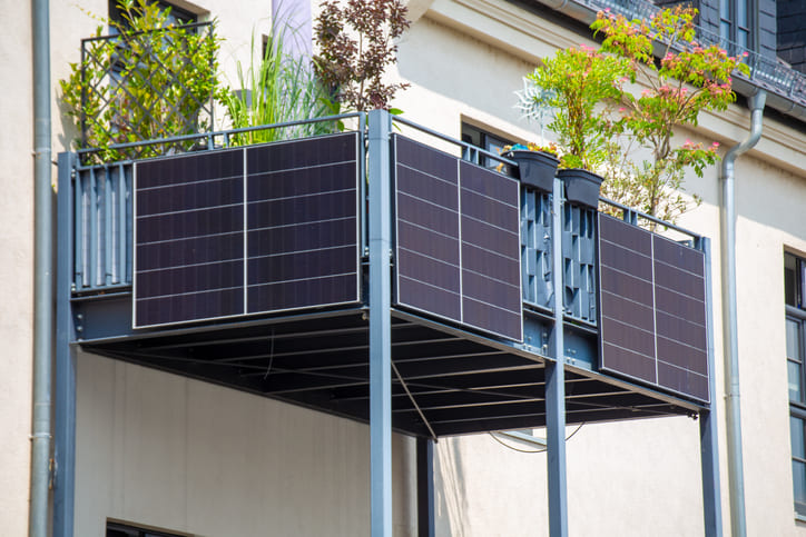 Balkon mit Grünpflanzen, darunter hängen Balkonkraftwerke.