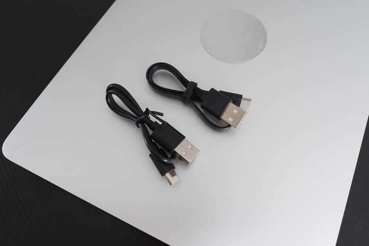 Geschlossener Laptop, darauf liegen zwei aufgewickelte USB-C Ladekabel, die als Neuerung ab April 2026 Pflicht sind.