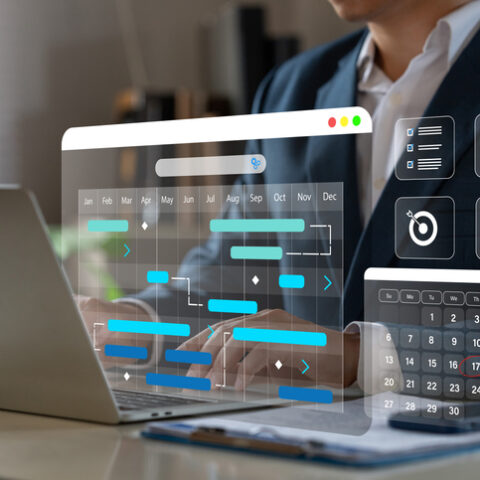 Anzugträger sitzt vor einem Laptop und prüft, ob die Arbeitszeit falsch erfasst ist. Davor schweben Diagramme mit Planungskalendern.