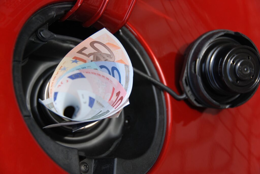 Euro-Scheine in einer Tanköffnung eines roten Autos symbolisieren die Neuerungen Juni 2026