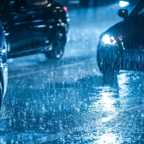 Bei Nacht muss ein Auto durch eine Pfütze fahren. Zwei weitere Autos nebendran, die Scheinwerfer leuchten.