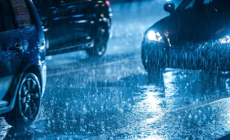 Bei Nacht muss ein Auto durch eine Pfütze fahren. Zwei weitere Autos nebendran, die Scheinwerfer leuchten.