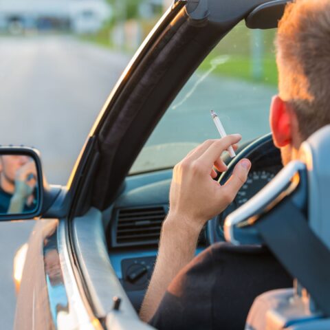 Ein Mann raucht Cannabis am Steuer, im Hintergrund ist die Autobahn.