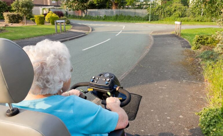 Eine Seniorin auf einem elektrischen Rollstuhl am Straßenrand hält die Promillegrenze für motorisierte Krankenfahrstühle ein.