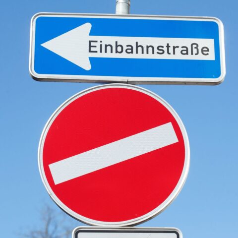 Irreführende Verkehrrsschilder, ein Einbahnstraßenschild und ein schiefes Einfahrt verboten Schild.
